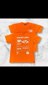 an orange t - shirt with a white label on it