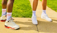 two people standing next to each other wearing white sneakers