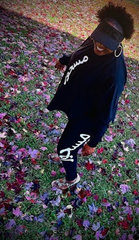 a woman wearing a black hat standing in a field of leaves