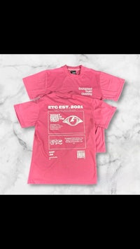 a pink t - shirt with a white label on it