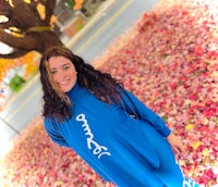 a woman in a blue shirt standing in front of a tree