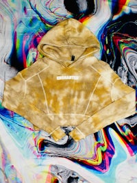 a yellow tie dye cropped hoodie on a colorful background