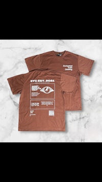 a brown t - shirt with an image of an eye on it