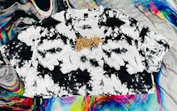 a black and white tie dye t - shirt on a colorful background